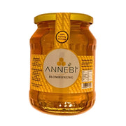 Lasipurkki, jossa on ANNEBI-kukkamehuni 900 g, kultaisen kellertävä luonnollinen hunaja etiketillä.