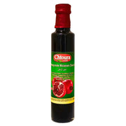 Pullo, jossa on granaattiomenasiirappia, idänomainen kastike vihreällä etiketillä ja punaisilla granaattiomenoilla.